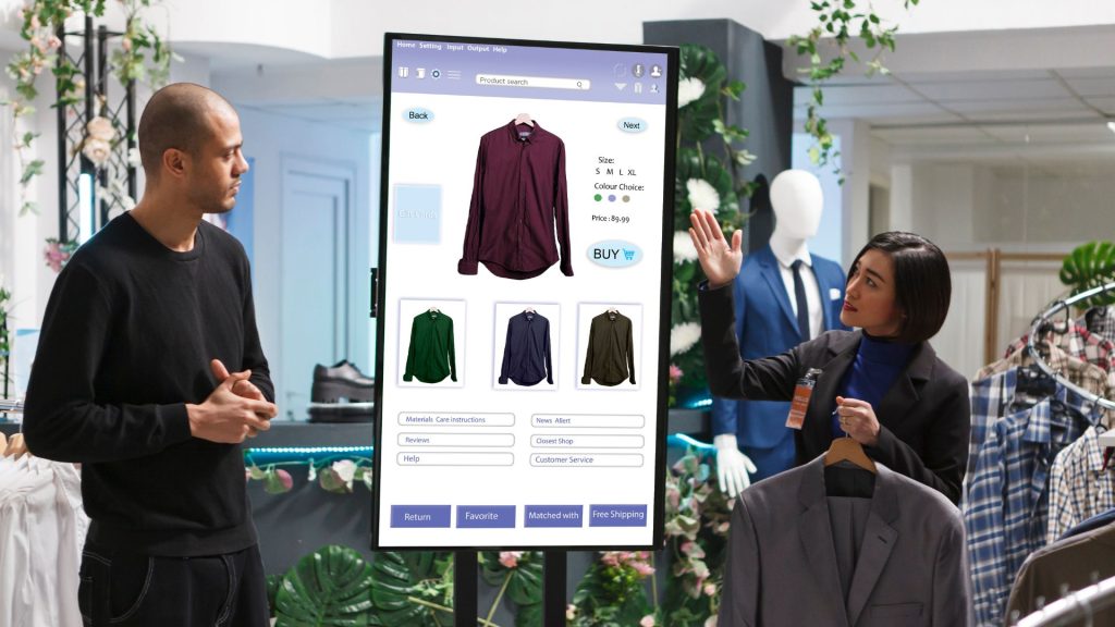 Retail associate demonstrating a smart AI-powered digital display to a customer in a clothing store, showcasing personalized shopping options
