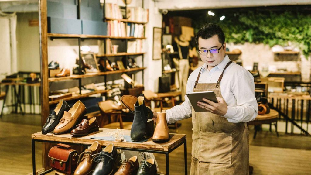 Retail store employee using a tablet to manage inventory and customer data in a shoe boutique