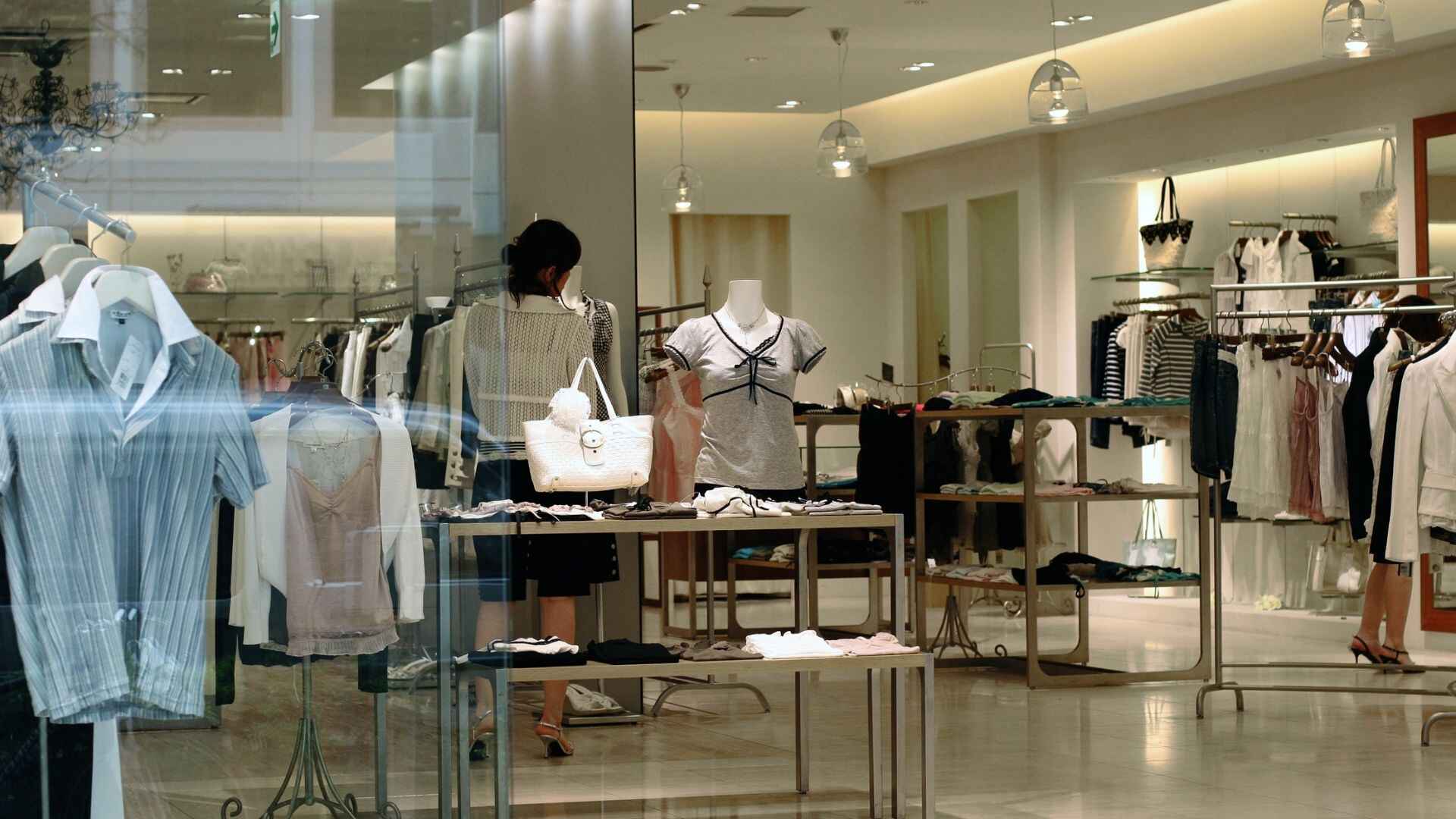 Interior view of a modern fashion retail store with clothing displays and mannequins